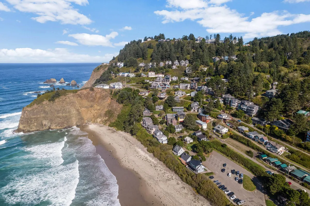 A tranquil exterior shot of cliffside homes, with dramatic rock formations, expansive beach, and ocean waves stretching into the horizon. The scene captures the sense of peacefulness and adventure, inviting guests to explore the nearby coastline.