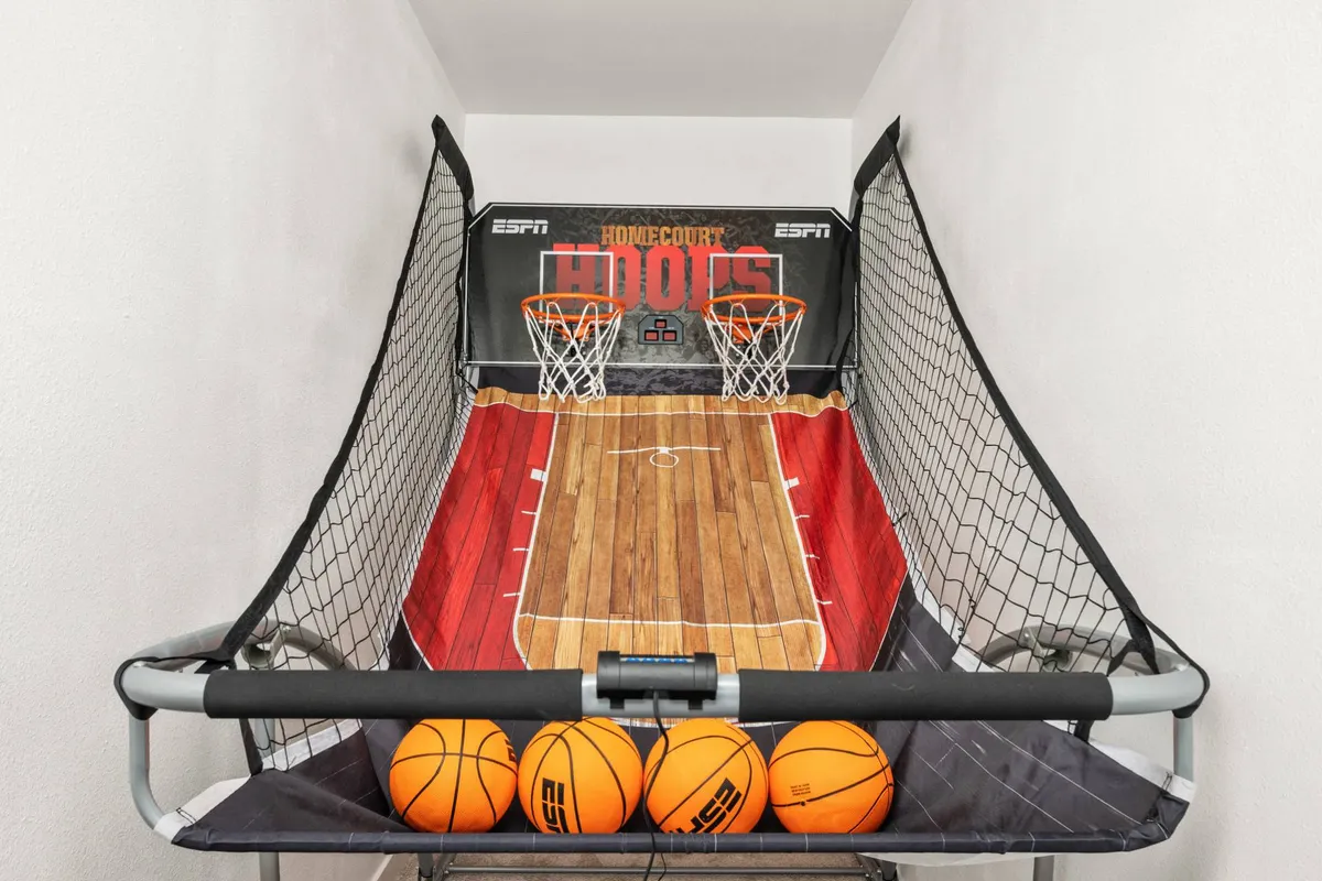 This interior shot centers on a basketball arcade game—also known as Pop-a-Shot—with basketballs ready for play and colorful wall graphics, creating an energetic, playful vibe. The surroundings suggest a dedicated game area perfect for family fun and friendly challenges.