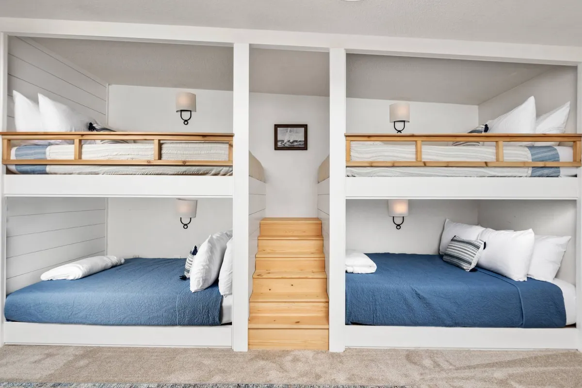 A cozy bunk room outfitted with full-over-full bunk beds, plush textiles, and a small staircase for easy access to the upper bunks. The inviting mood suggests a fun, family-friendly space ideal for kids to enjoy late-night talks and game nights.