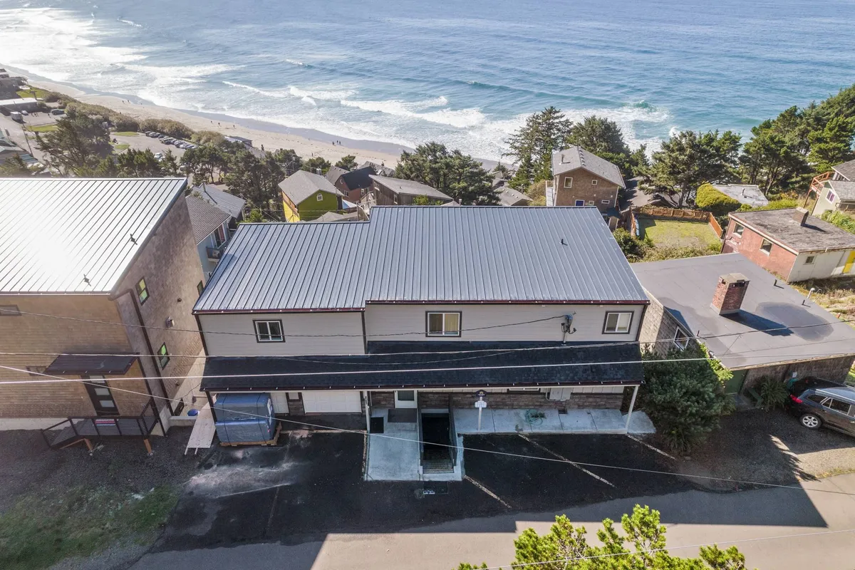 An exterior shot of the house with an expansive view of the ocean, nearby beach access, and surrounding trees. The home feels inviting, perfectly situated for families looking to make the most of both outdoor and indoor spaces.