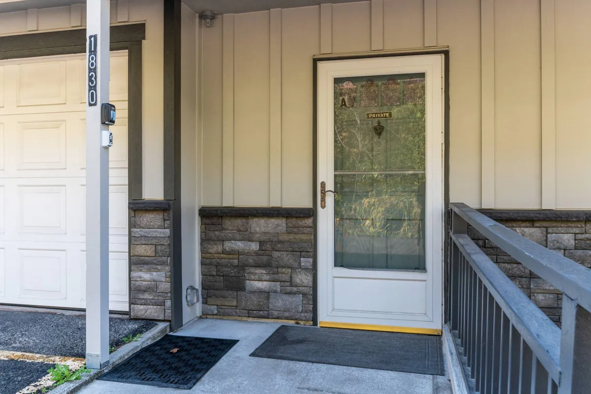 An inviting entrance view with the front door, a welcoming stone wall, and a doormat, suggesting a friendly arrival experience for both people and pets.