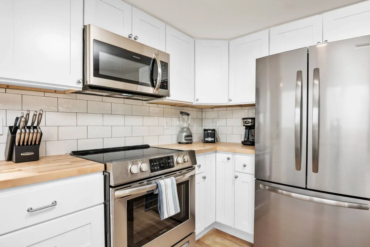 This image focuses on a modern kitchen with stainless steel appliances, wooden countertops, and white cabinetry. The space feels inviting and practical, ready for culinary adventures such as preparing fresh finds from local markets and seafood shops.